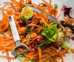 Vegetable food scraps with carrot skins and a vegetable peeler